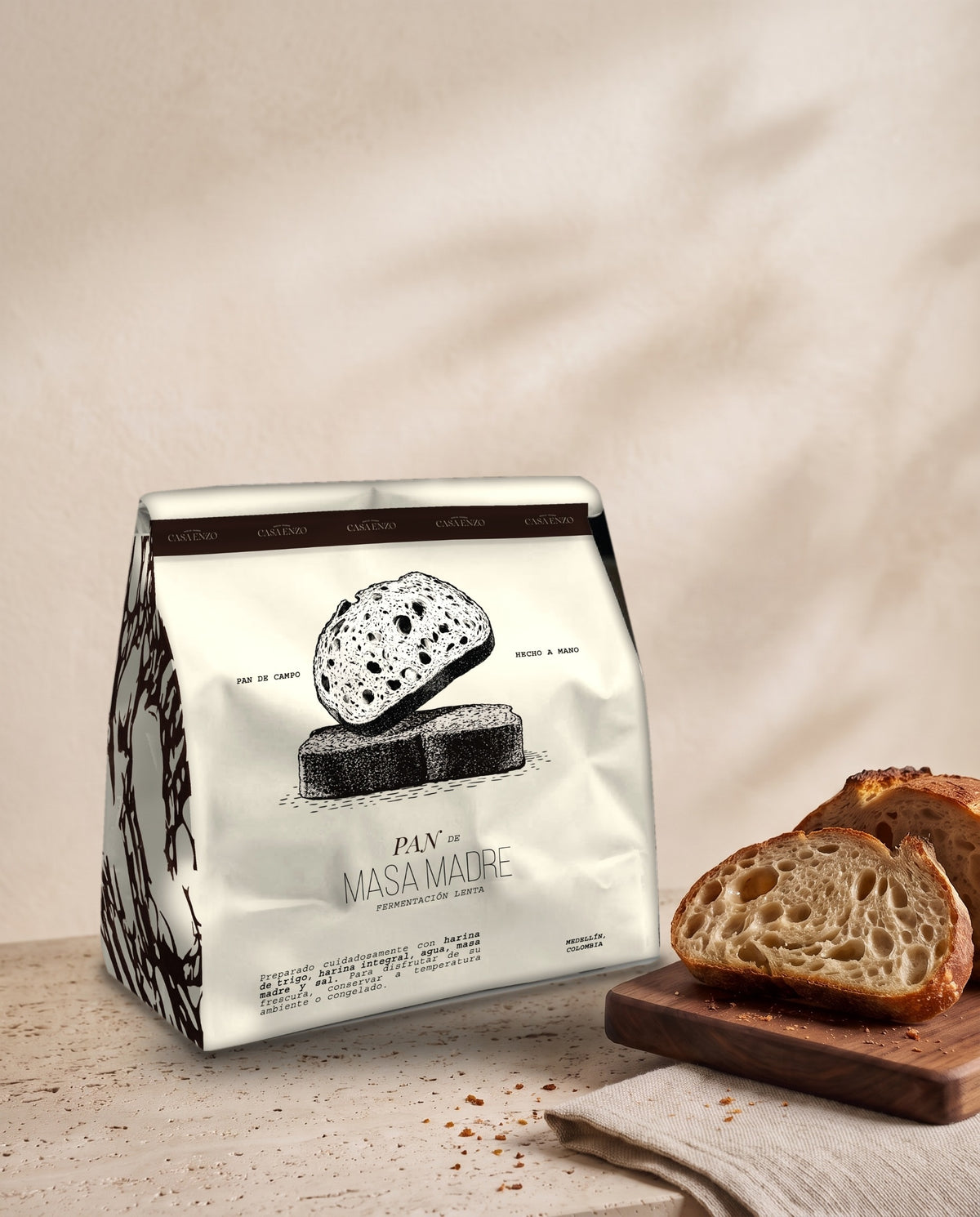 Bolsa de Pan de Masa Madre Casa Enzo, fermentación lenta, sobre travertino junto a tajadas de pan